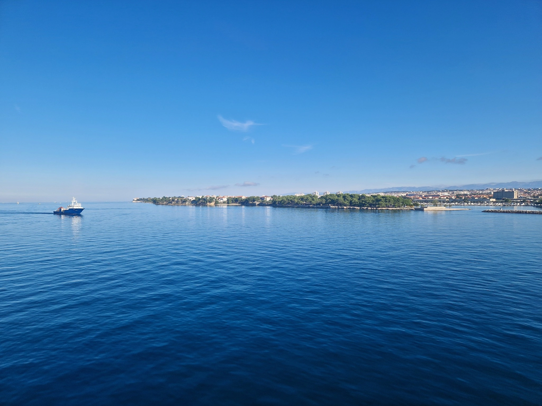 Ruhiges blaues Meer mit Boot und Blick auf die Küste während unserer Reise.
