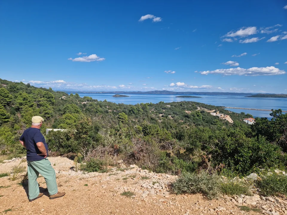 Opa steht beim Grundstücksbesuch mit Blick über die Landschaft und das Meer.